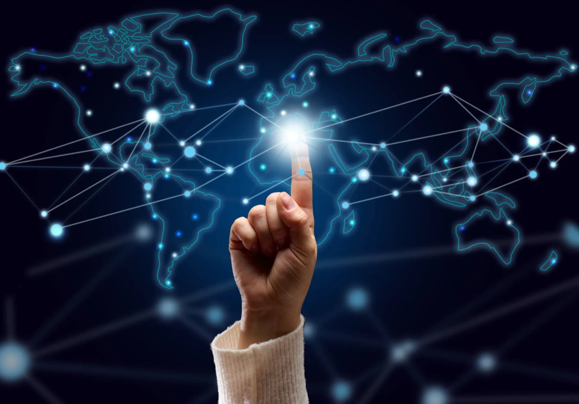 A hand presses a glowing point on a holographic world map, lines connecting nodes across every continent